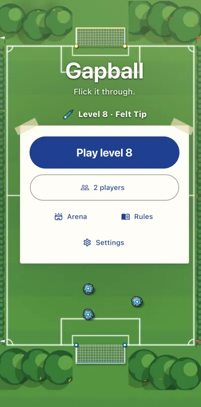 The Gapball home screen on a green pitch with white lines and trees in the corners: a paper card with the Play button, and three paper balls on the grass.